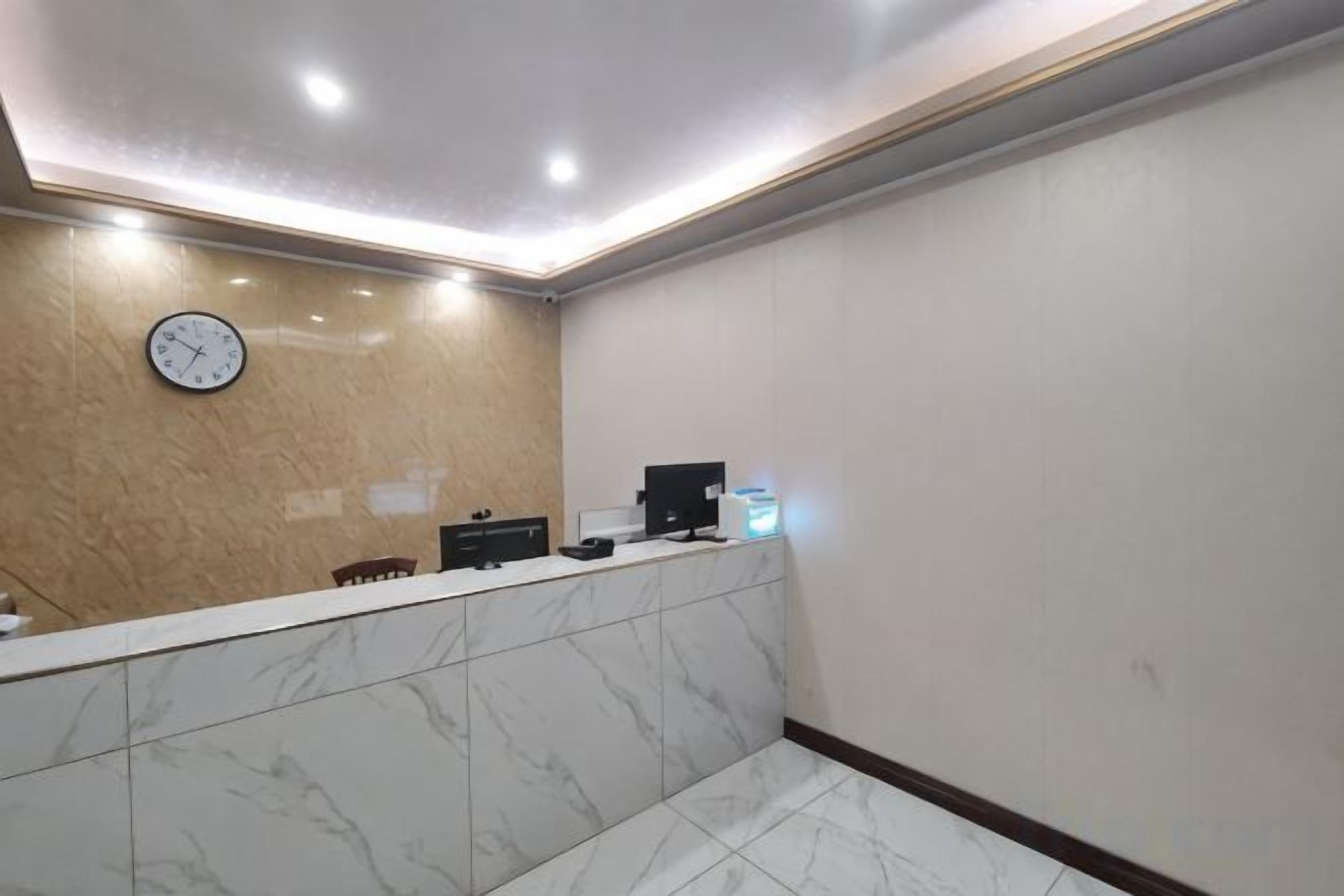 A reception area with a marble counter, a clock, and a computer monitor.