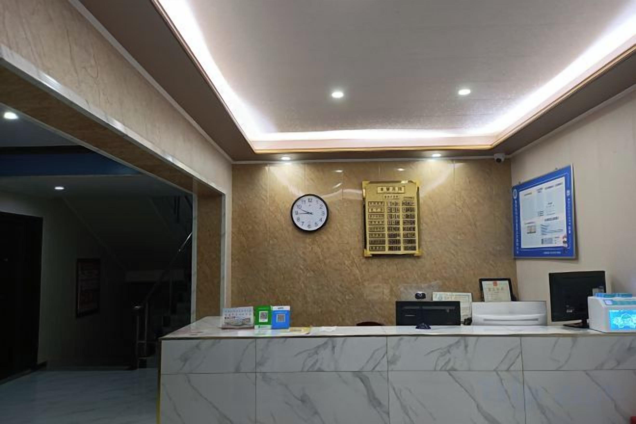 A reception area with a marble counter, a clock, a bulletin board, and a framed notice on the wall.