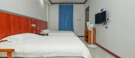 A hotel room with a bed, a chair, a TV, and a curtain.
