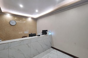 A reception area with a marble counter, a clock, and a computer monitor.