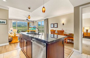 A kitchen with a large island, a dining area with a view, and a bar area.