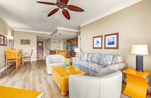 Ein Wohnzimmer mit Deckenventilator, einer Couch, einem Couchtisch und einem Essbereich mit Stühlen und Tisch.