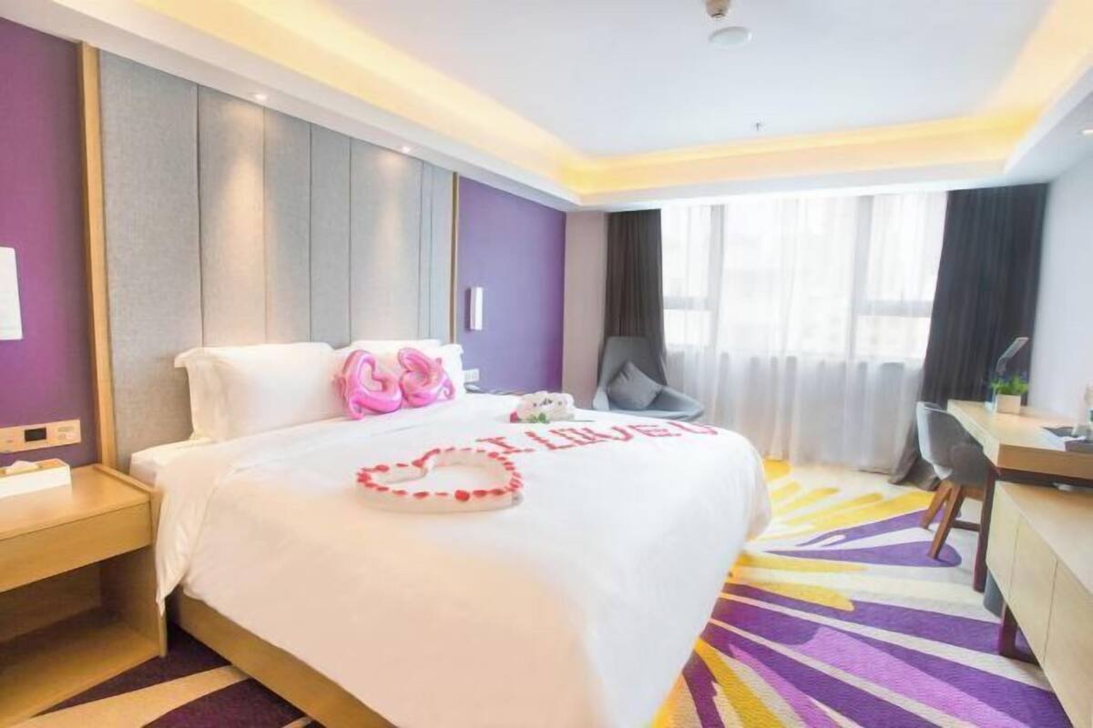 Ein Hotelzimmer mit Bett, Schreibtisch, Stuhl und einem fensterbepflanzten Fenster.