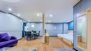 A hotel room with a purple sofa, a dining table with chairs, a small kitchen area, and a bed. - Yijia Hotel (Ji'an No.2 Middle School Pedestrian Street) (Ji'an)