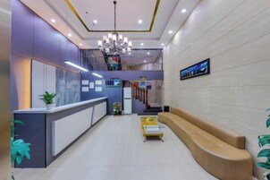 Un área de recepción con mostrador, asientos, una escalera y una pantalla de televisión.