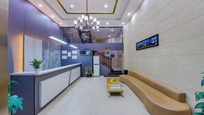 A modern reception area with a reception desk, seating area, and a staircase leading to an upper level. - Yijia Hotel (Ji'an No.2 Middle School Pedestrian Street) (Ji'an)