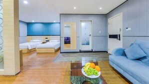 A modern hotel room with a bed, a sofa, a glass coffee table with fruit, and a bathroom visible through a glass door. - Yijia Hotel (Ji'an No.2 Middle School Pedestrian Street) (Ji'an)