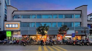 A hotel with a modern facade, multiple floors, and a row of parked scooters in front. - Yijia Hotel (Ji'an No.2 Middle School Pedestrian Street) (Ji'an)