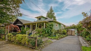 Une maison verte avec un porche, une clôture en bois et un chemin qui traverse le jardin.