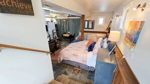 A bedroom with a bed, bedside table, lamp, and artwork on the wall. - #StayinMyDistrict Hyde Park Northend Studio (Boise)