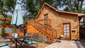 A wooden cabin with a balcony, a staircase, and a patio area with outdoor seating. - #StayinMyDistrict Hyde Park Northend Studio (Boise)
