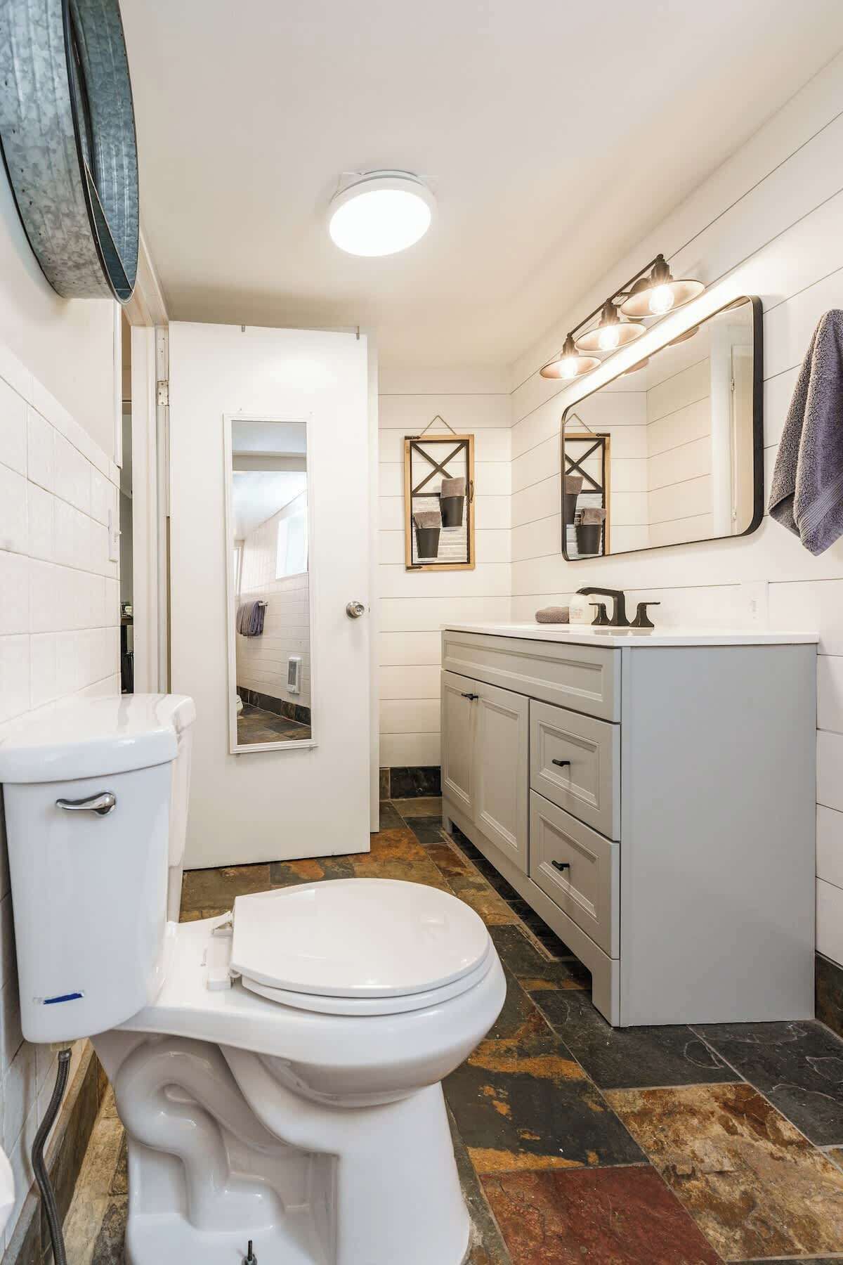 A bathroom with a white toilet, a sink with a mirror, and a shower area.