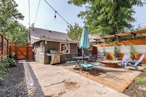 A backyard with a barbecue area, outdoor seating, and a pergola.