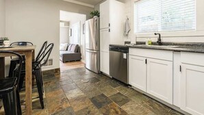 Una cocina moderna con armarios blancos, lavavajillas y refrigerador.