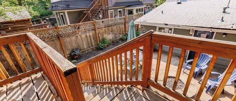 A wooden deck with a view of a house and a fenced yard.