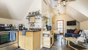 Een kleine keuken met een centraal eiland, een eethoek met een stoel, en een woonkamer met een bank en een televisie.