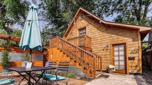Een houten chalet met een balkon, buitenmeubels en een trap naar de ingang.