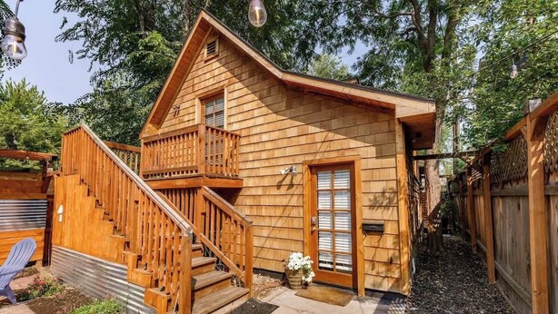 Een houten hut met een houten trap die naar een balkon leidt.