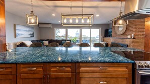 A kitchen with a large granite island, wooden cabinets, and a stainless steel range hood. - #StayInMyDistrict Garibaldi Bay Views (Garibaldi)