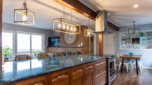 A modern kitchen with a large island, wooden cabinets, and pendant lighting. - #StayInMyDistrict Garibaldi Bay Views (Garibaldi)