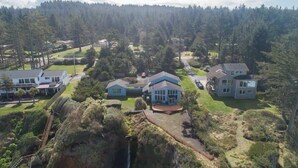 A residential area with multiple houses, a waterfall, and a forested hill in the background. - #StayinMyDistrict Cape Arago Studio Suite (Coos Bay)