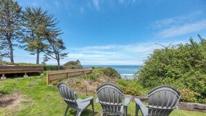 A grassy outdoor area with three Adirondack chairs facing a view of the ocean. - #StayinMyDistrict Cape Arago Studio Suite (Coos Bay)