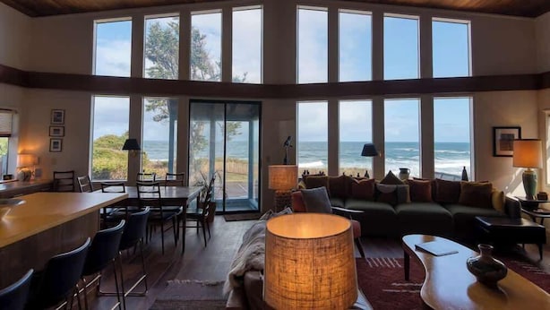 Een ruime woonkamer met een groot raam met uitzicht op de oceaan, een gezellige zithoek en een bar.