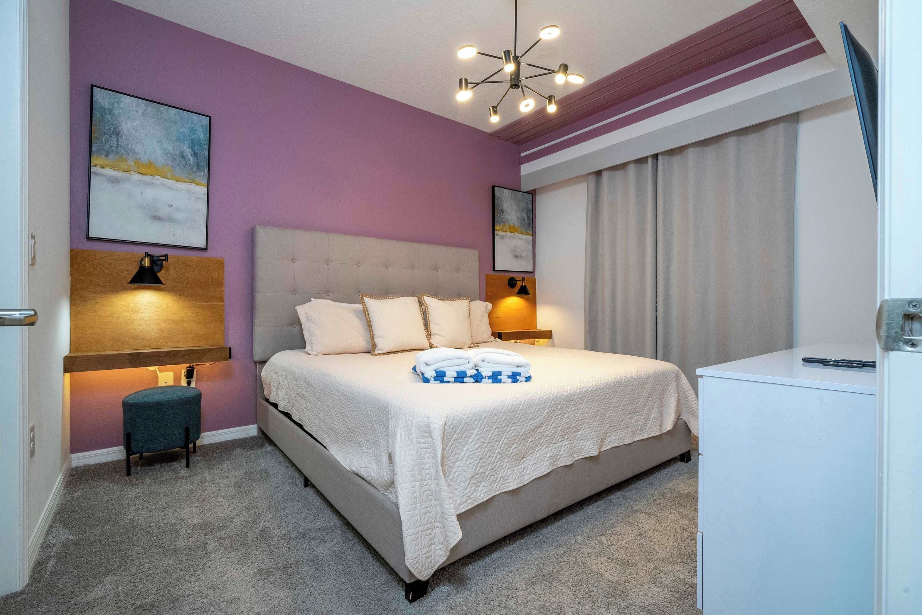 A bedroom with a bed, bedside lamps, a desk, and a chair.