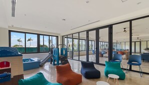 Relax in a spacious lounge area with a high ceiling and large windows offering a view of palm trees and the sky.