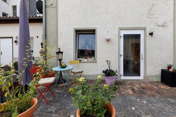 A courtyard with potted plants, a small table, and a chair.