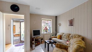 Una sala de estar con sofá, televisión y ventana con vistas.
