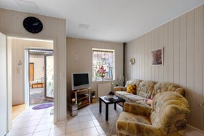 Sala de estar com sofá, televisão e janela com vista.