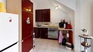 Cocina compacta con refrigerador, estufa, horno y alacenas.