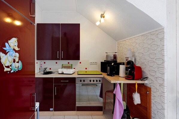 Una cocina compacta con estufa, horno y cafetera en la encimera.