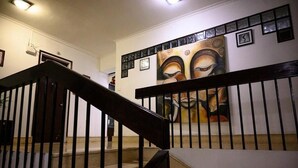 Un escalier avec une rampe noire et une grande peinture abstraite accrochée au mur au-dessus.