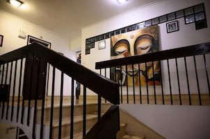 Una escalera con barandilla negra y un cuadro abstracto de grandes dimensiones en la pared superior.