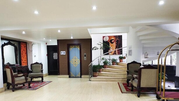 Un hall d’entrée spacieux avec un sol en marbre, un escalier agrémenté de plantes en pot et un comptoir d’accueil.