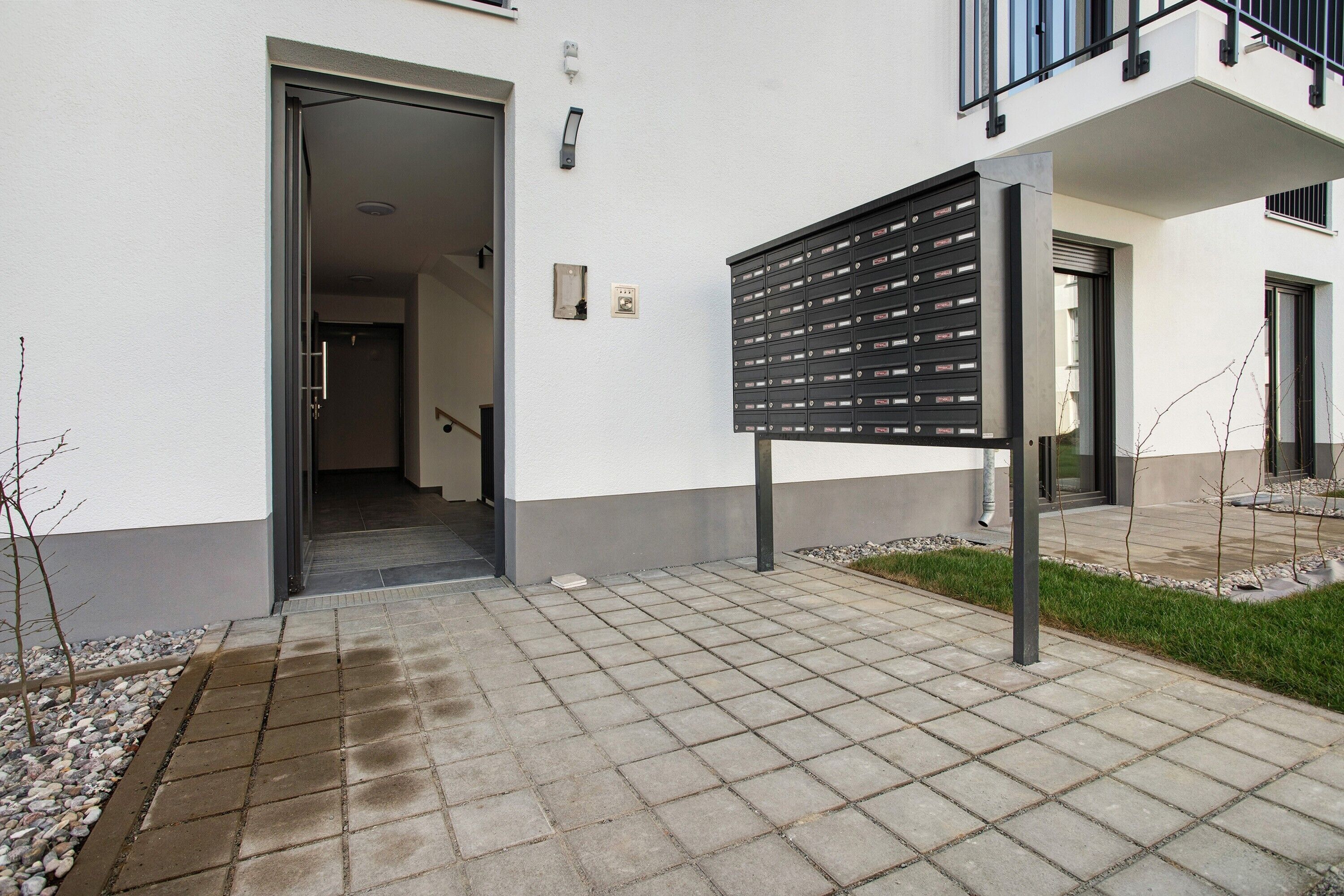 Entrada de un edificio con buzón, puerta y un pequeño jardín.