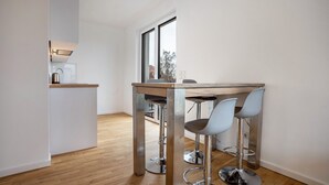 A modern kitchen with a wooden countertop, stainless steel appliances, and two bar stools.