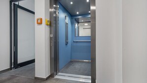 Een lift met een blauw interieur, een handgreep en een deur met een ruit.