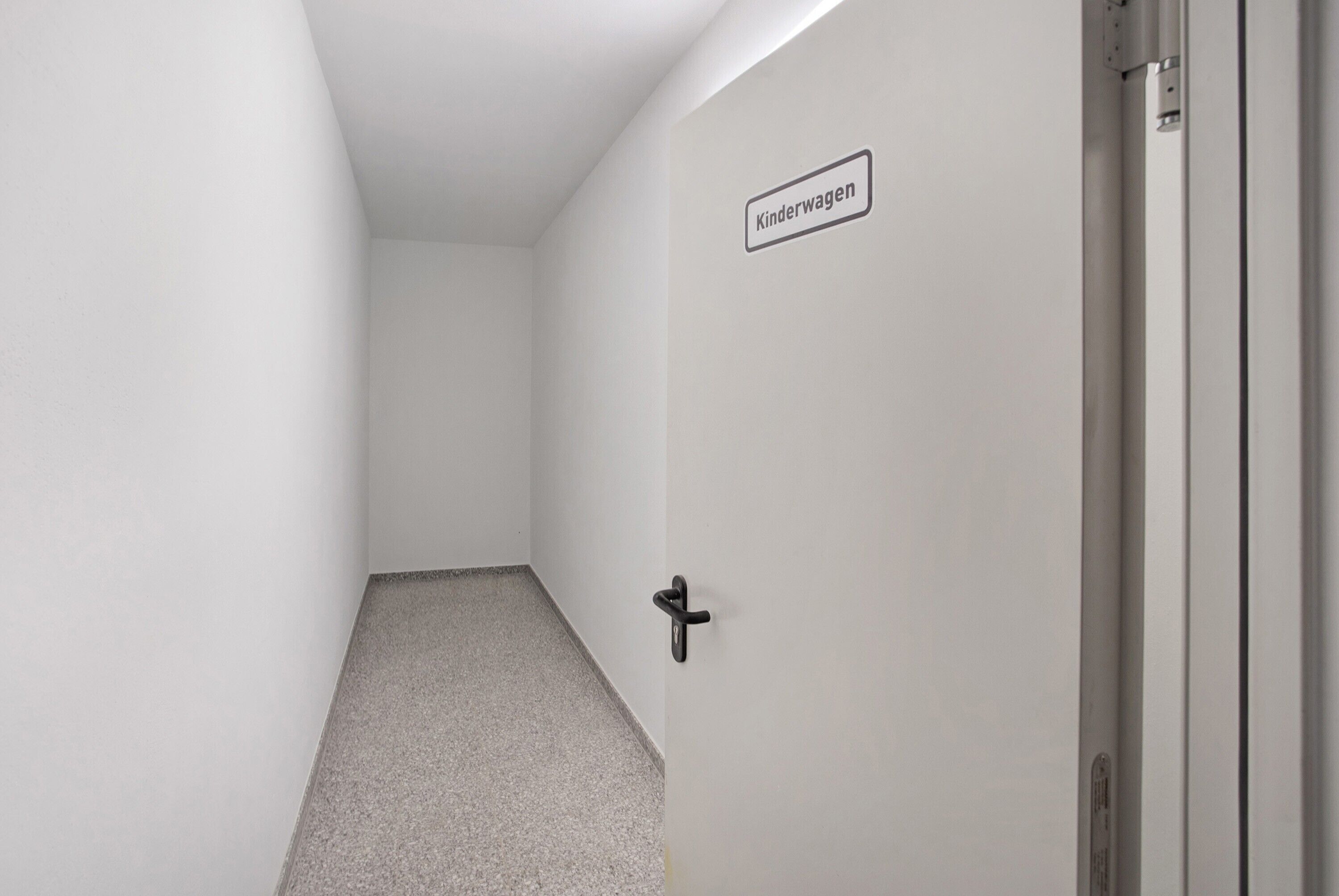 A hallway with a door labeled 'Kinderwagen' and a black handle.
