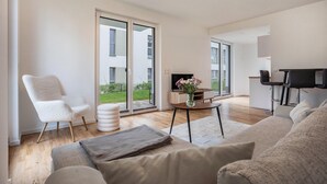 A modern living room with a sofa, a chair, a small table with a vase, and a TV.