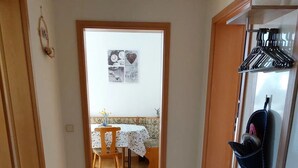 A hallway leading to a dining area with a table and chairs, a coat rack, and a small bench. - Apartment 'Giesis Wohlfühloase' with Shared Terrace, Private Garden and Wi-Fi (Döbeln)