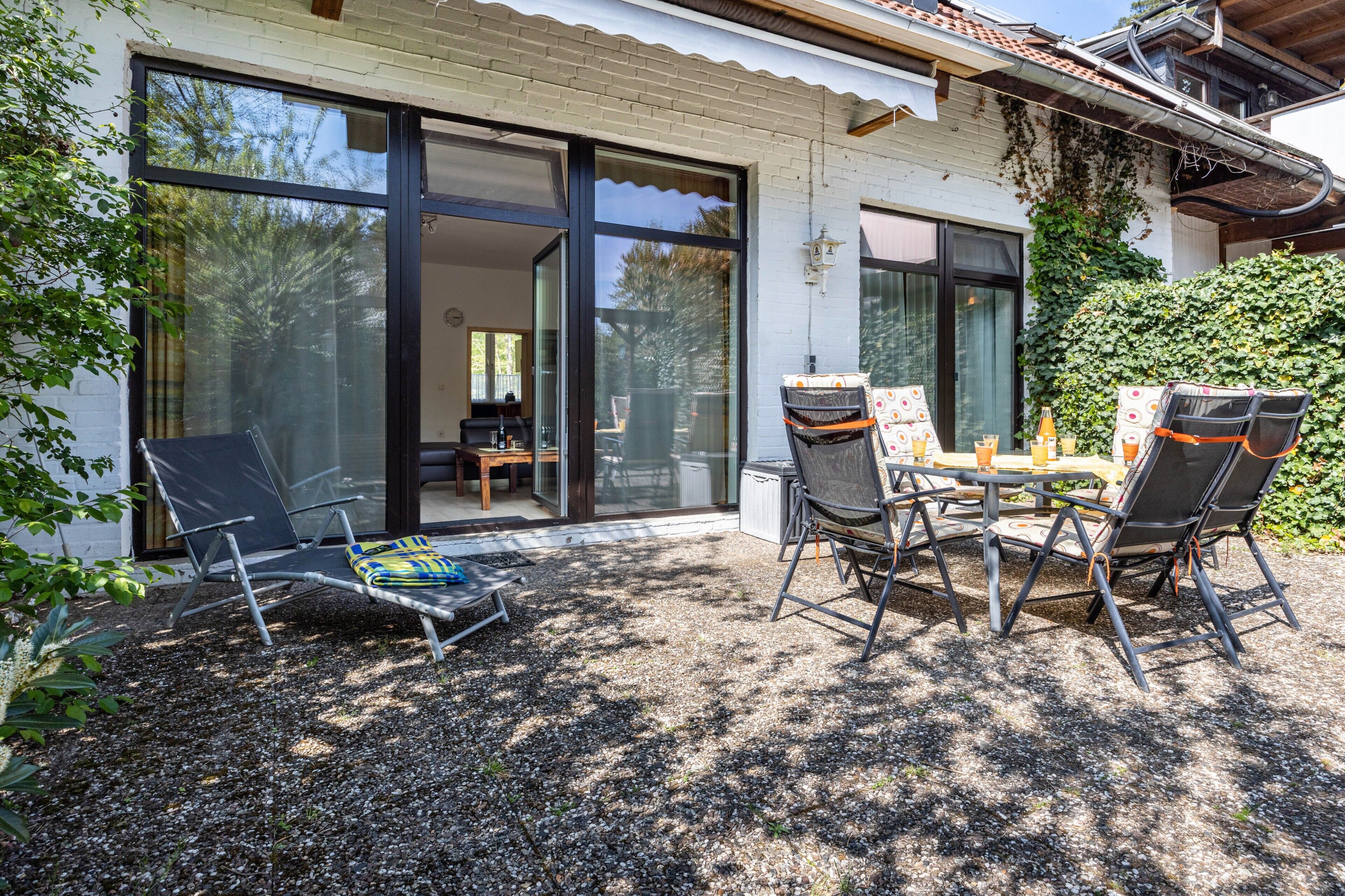 Een terras met tuinmeubilair, een tafel en een stoel.