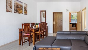 Ein Wohnzimmer mit einer Couch, einem Esstisch, Stühlen und Bildern an der Wand.