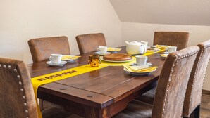 Un tavolo da pranzo con sedie, un runner giallo e una teiera bianca.
