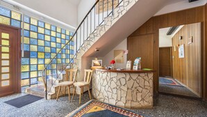 Una hall con una scala in pietra, una reception e un tappeto decorato.
