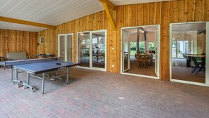 An indoor ping pong table with a wooden wall and glass doors leading to an outdoor area. - Holiday Apartment 5 with Private Terrace, Private Garden and Wi-Fi (Mardorf)