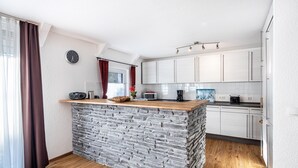 A kitchen with a stone island, white cabinets, and a clock on the wall. - Holiday Apartment 5 with Private Terrace, Private Garden and Wi-Fi (Mardorf)