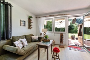 A cozy living room with a sofa, a table, and a view of the outdoors through large windows. - Cosy Holiday Apartment in an idyllic location in Todtmoos (Todtmoos)